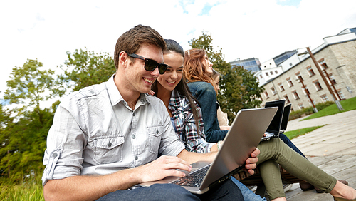 summer, communication, technology , education and teenage concept - group of students or teenagers with laptop computers at park or campus