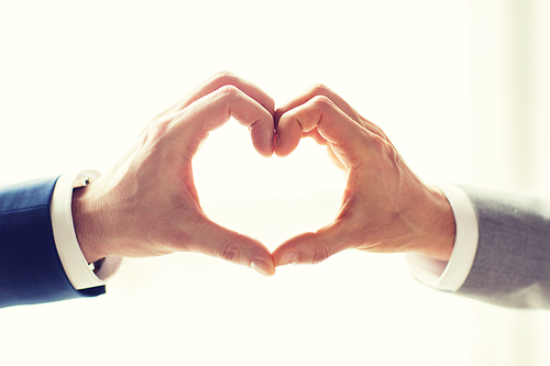 people, homosexuality, same-sex marriage, gesture and love concept - close up of happy male gay couple hands showing heart hand sign