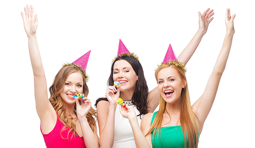 celebration, friends, bachelorette party, birthday concept - three smiling women wearing pink hats and blowing favor horns and waving hands