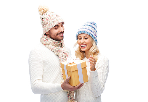 winter, holidays, couple, christmas and people concept - smiling man and woman in hats and scarf with gift box