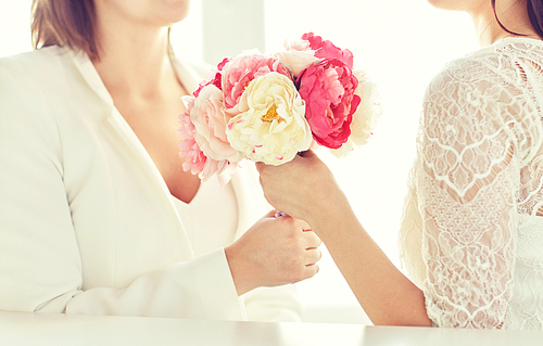 people, homosexuality, same-sex marriage and love concept - close up of happy married lesbian couple with flower bunch