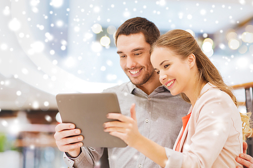 shopping, technology and people concept - happy couple with tablet pc taking selfie in mall or business center with snow effect