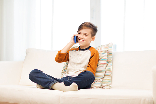 leisure, children, technology, communication and people concept - smiling boy calling on smartphone at home