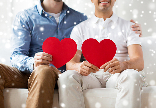 people, homosexuality, same-sex marriage, valentines day and love concept - close up of happy gay male couple with red hearts at home over snow effect