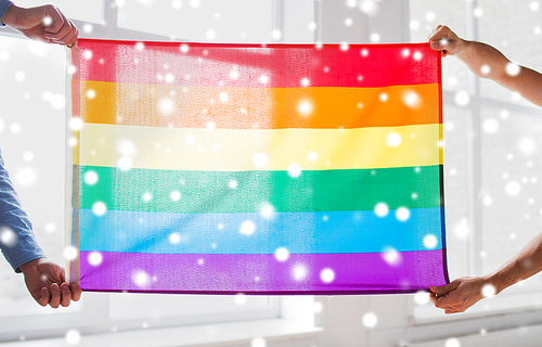 people, homosexuality, same-sex, gay and love concept - close up of happy male gay couple hugging and holding rainbow flag at home over snow effect