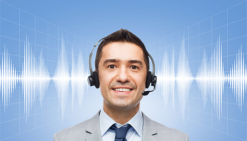 business, people, technology and service concept - smiling businessman in headset over sound wave or signal diagram on blue background