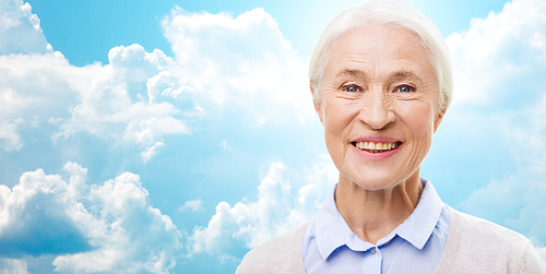 age and people concept - happy smiling senior woman face over blue sky and clouds background