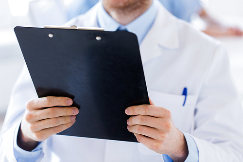 profession, people, health care and medicine concept - close up of male doctor with clipboard at hospital