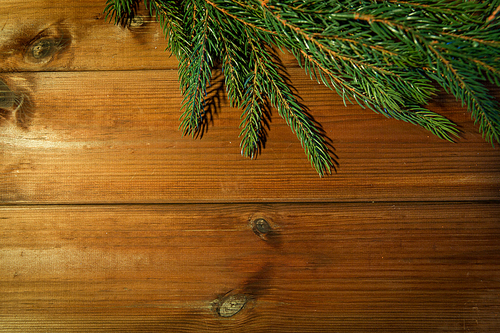 christmas, decoration, holidays and advertisement concept - close up of natural fir branch on blank brown wooden board