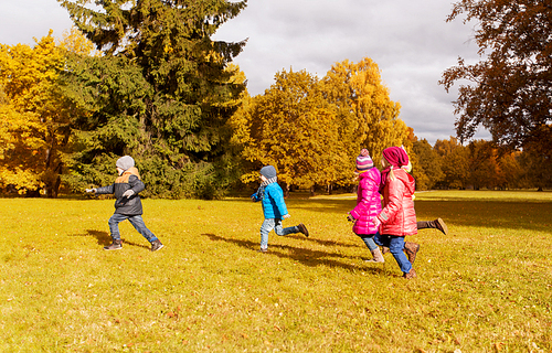 autumn, childhood, leisure and people concept - group of happy little kids playing tag game and running in park outdoors