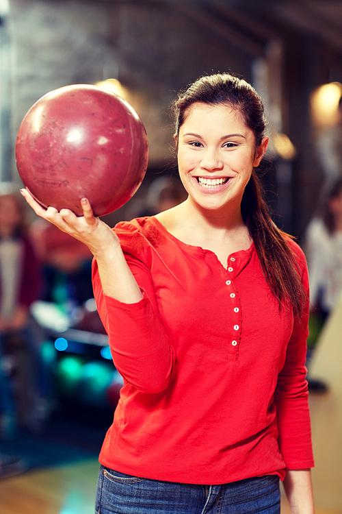 people, leisure, sport and entertainment concept - happy young woman holding ball in bowling club