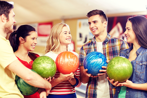 people, leisure, sport, friendship and entertainment concept - happy friends holding balls and talking in bowling club