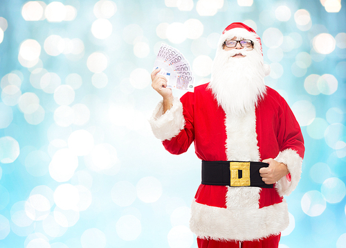 christmas, holidays, winning, currency and people concept - man in costume of santa claus with euro money over blue holidays lights background