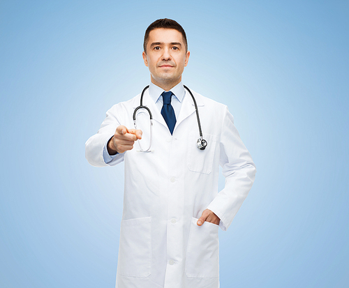 healthcare, profession, gesture, people and medicine concept - male doctor in white coat with stethoscope pointing at you over blue background