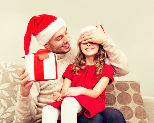 family, christmas, x-mas, winter, happiness and people concept - smiling father surprise daughter with gift box covering eyes with hand