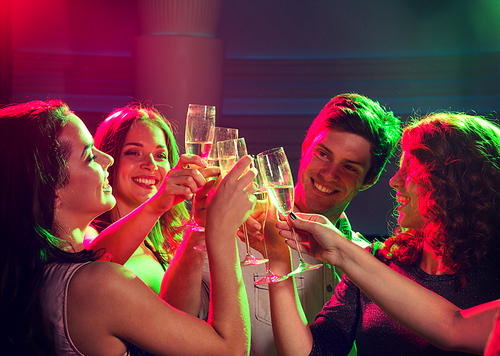 party, holidays, celebration, nightlife and people concept - smiling friends with glasses of champagne in club