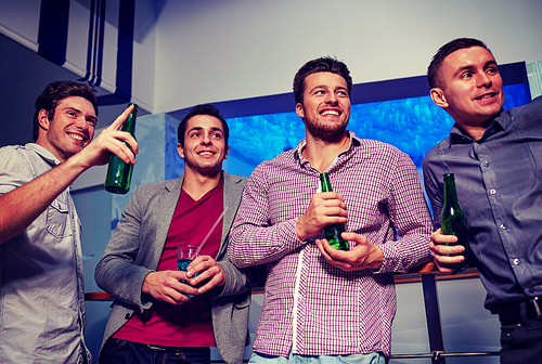 nightlife, party, friendship, leisure and people concept - group of smiling male friends with beer bottles drinking in nightclub