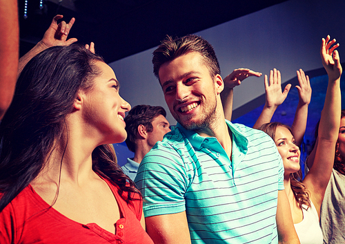 party, holidays, celebration, nightlife and people concept - smiling friends waving hands at concert in club