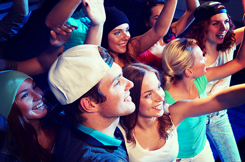 party, holidays, celebration, nightlife and people concept - smiling friends waving hands at concert in club