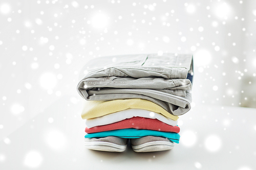 clothes, personal staff and objects concept - close up of folded shirts, pants and shoes on table at home