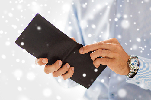 people, business, finances and money concept - close up of businessman hands holding open wallet over snow effect