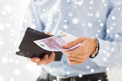 people, business, finances and money concept - close up of businessman hands holding open wallet with euro cash over snow effect