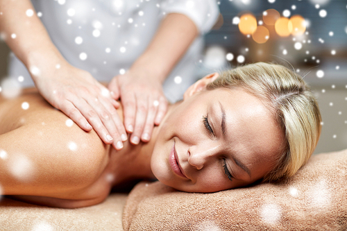 people, beauty, spa, winter and relaxation concept - close up of beautiful young woman lying with closed eyes and having hand back massage in spa salon with snow effect