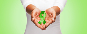 healthcare and medicine concept - close up of woman hands holding green organ transplant awareness ribbon