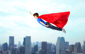 imagination, freedom, childhood, movement and people concept - boy in red superhero cape and mask flying in air over city background