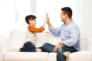family, gesture, fatherhood, generation and people concept - happy father and son doing high five at home
