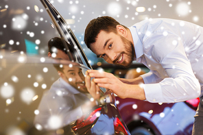 auto business, car sale, consumerism and people concept - happy man touching car in auto show or salon over snow effect