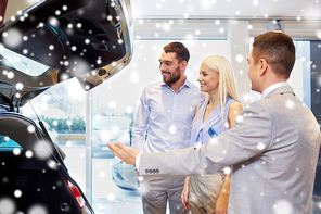 auto business, car sale and people concept - happy couple with car dealer in auto show or salon over snow effect
