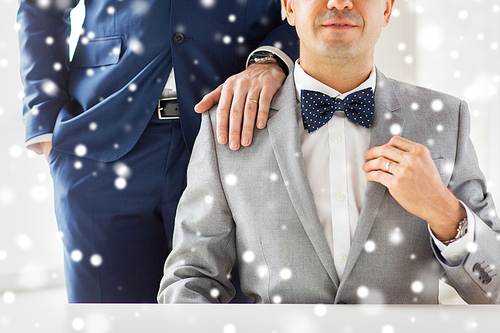 people, celebration, homosexuality, same-sex marriage and love concept - close up of male gay couple with wedding rings on putting hand on shoulder over snow effect