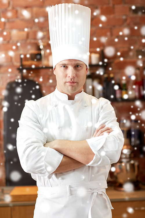 cooking and people concept - happy male chef cook with crossed hands in restaurant kitchen over snow effect