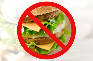 fast food, low carb diet, fattening and unhealthy eating concept - close up of hamburger or cheeseburger behind no symbol or circle-backslash prohibition sign