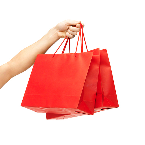 people, sale, consumerism, advertisement and commerce concept - close up of hand holding red blank shopping bags