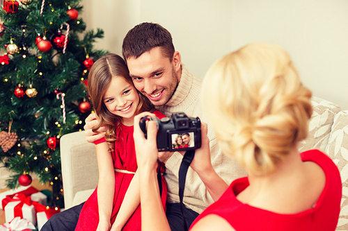 family, christmas, x-mas, happiness and people concept - mother taking picture of smiling father and daughter