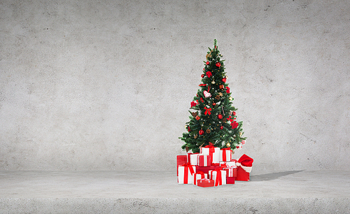 celebration, winter holidays and advertisement concept - christmas tree with gifts and santa hat over concrete wall background