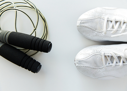 sport, fitness, healthy lifestyle, cardio training and objects concept - close up of sneakers and skipping rope