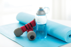 sport, fitness, healthy lifestyle and objects concept - close up of bottle with water, dumbbells and sports mat