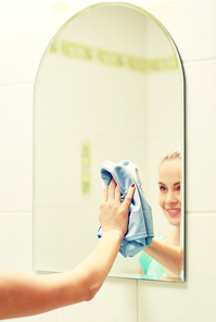 people, housework and housekeeping concept - close up of happy woman cleaning mirror with rag at home