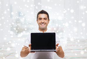 technology, people lifestyle and networking concept - happy man showing laptop black blank screen at home over snow effect
