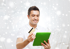 technology, people, online shopping and finances concept - happy man with tablet pc computer and credit card at home over snow effect