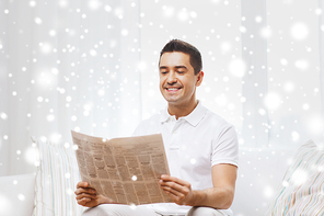 leisure, information, people and mass media concept - happy man reading newspaper at home with snow effect