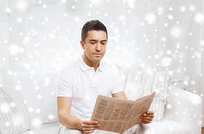 leisure, information, people and mass media concept - man reading newspaper at home with snow effect