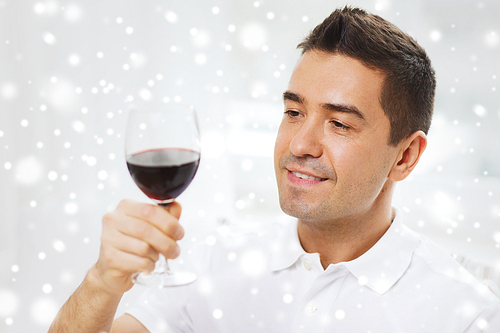 profession, drinks, leisure, holidays and people concept - happy man  red wine from glass over snow effect