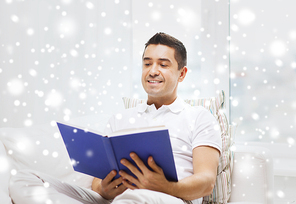 leisure, education, literature and people concept - happy man reading book at home over snow effect