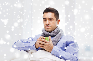 health care, people, winter and medicine concept - ill man with flu drinking hot tea from cup at home over snow effect