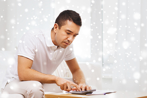business, savings, finances and people concept - man with papers and calculator at home over snow effect