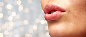 beauty, people, make-up and plastic surgery concept - close up of young woman lips over holidays lights background